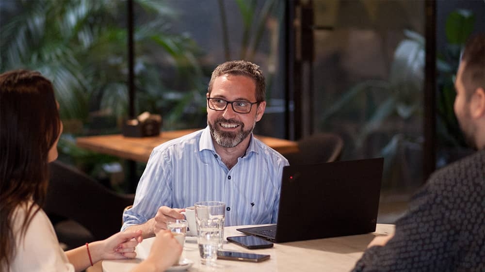 Person in a coffee shop with a computer smiling